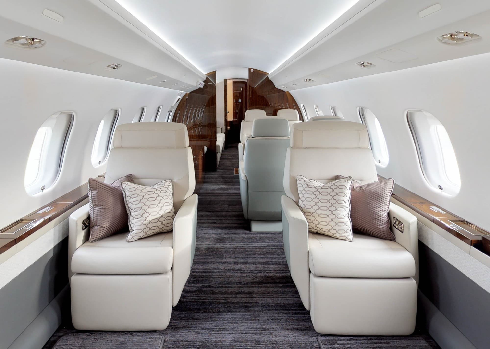 Cream leather club seats with cushions either side of the aisle in a large private jet cabin